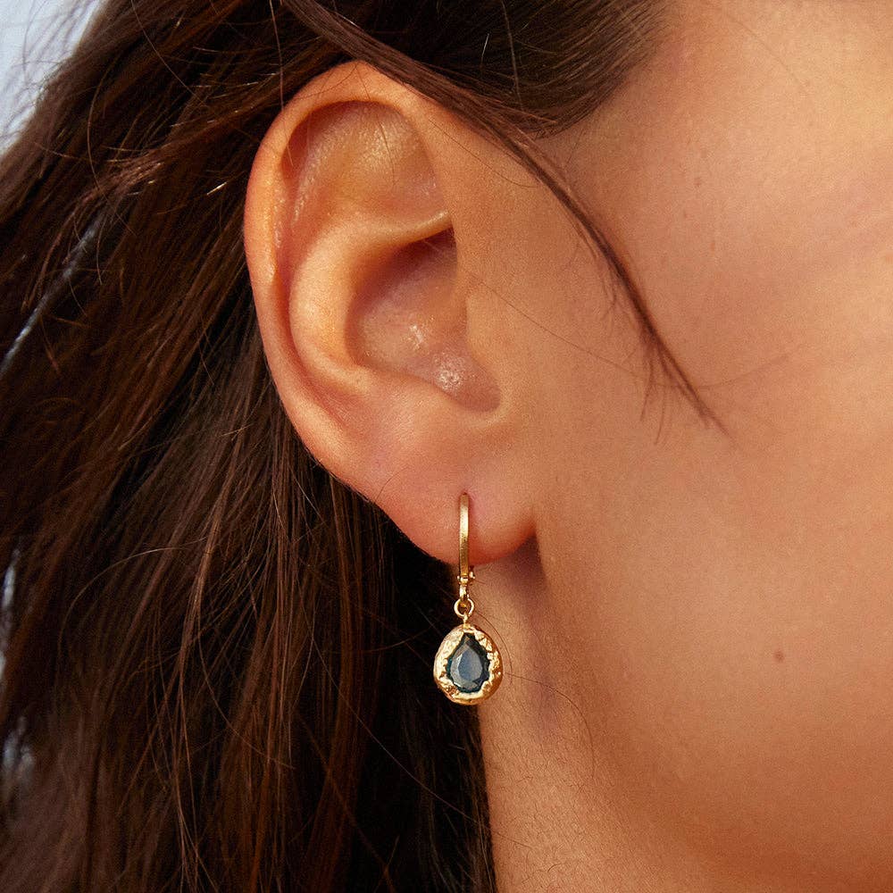 Gold earrings with green gemstones on a white background