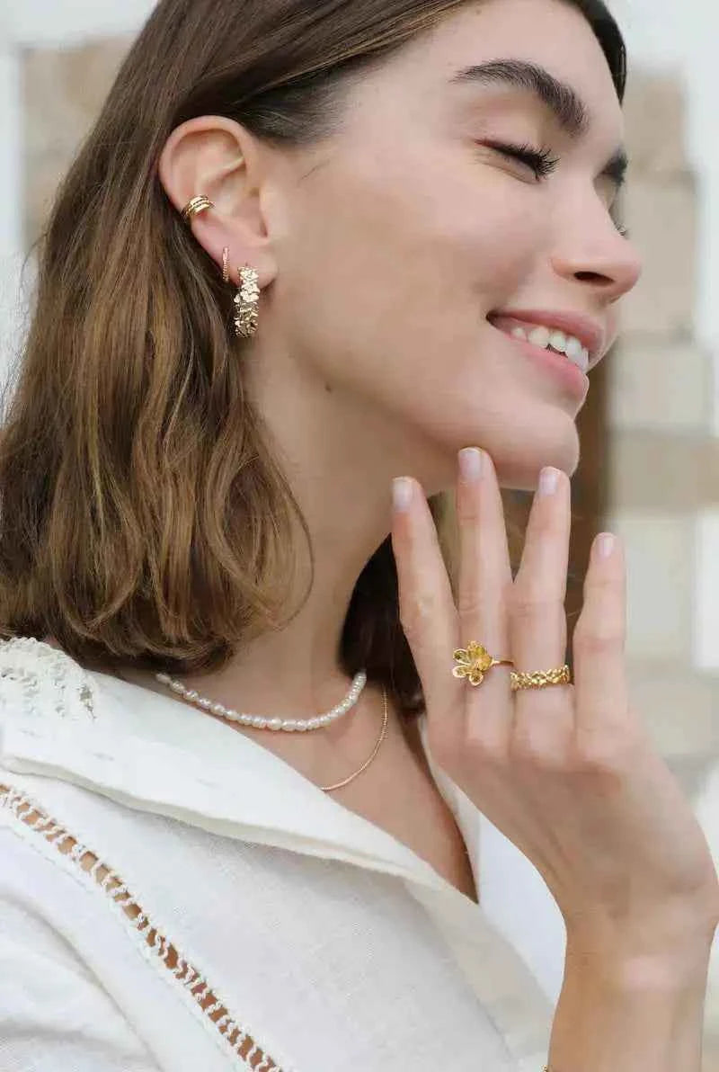 Elegant gold-tone floral statement earrings featuring an intricate botanical-inspired pattern and sophisticated design