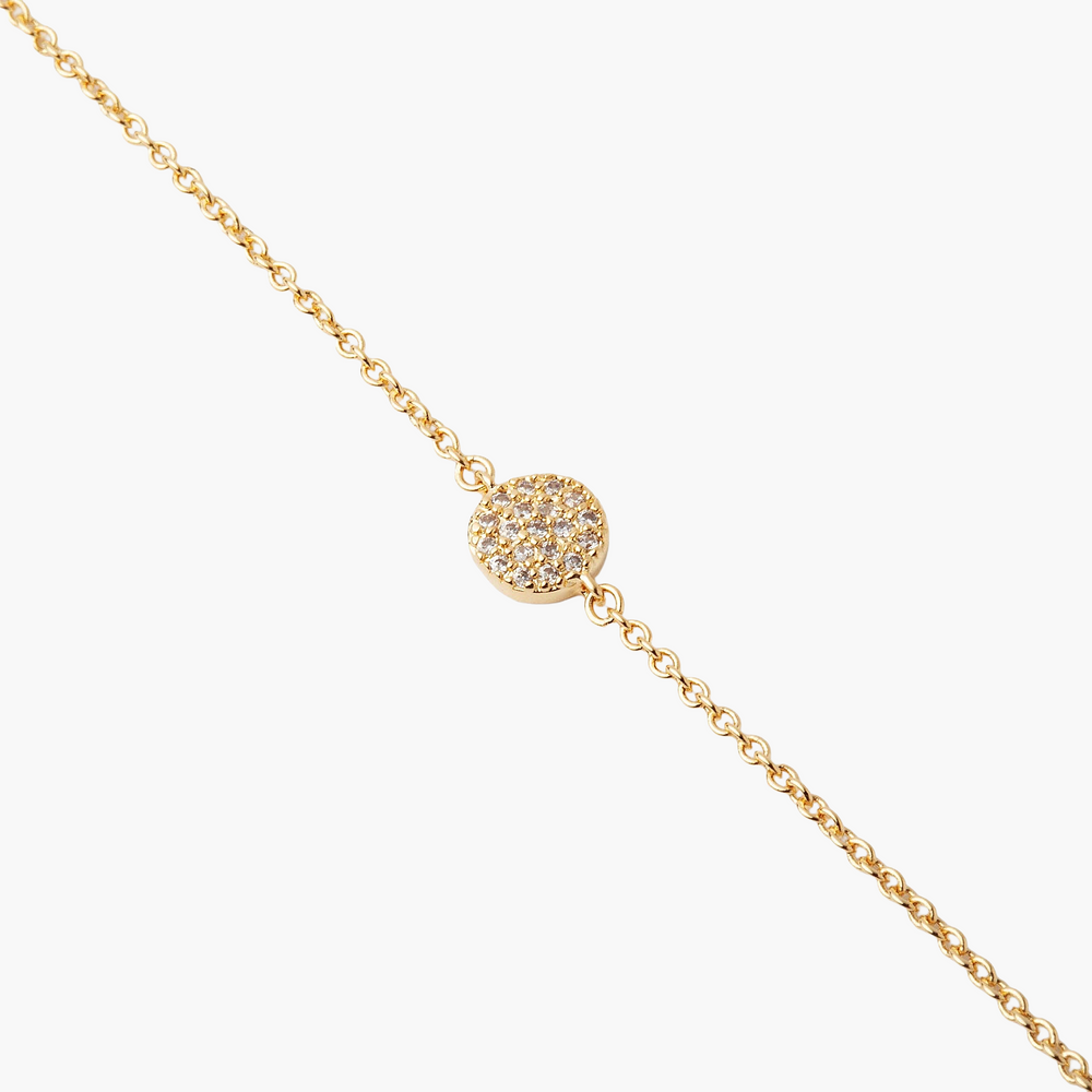 Gold necklace with a round, diamond-studded pendant on a white background