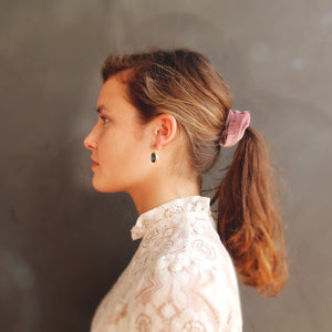 Woman with a ponytail wearing a lace top against a neutral background