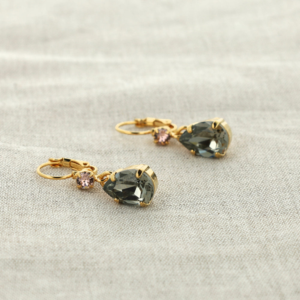 Pair of gold earrings with green teardrop-shaped gemstones on a white background