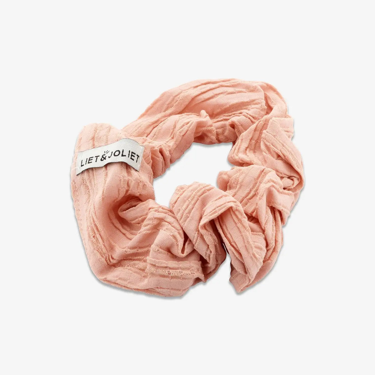 Salmon pink scrunchie made from soft satin fabric for an elegant and stylish hair accessory