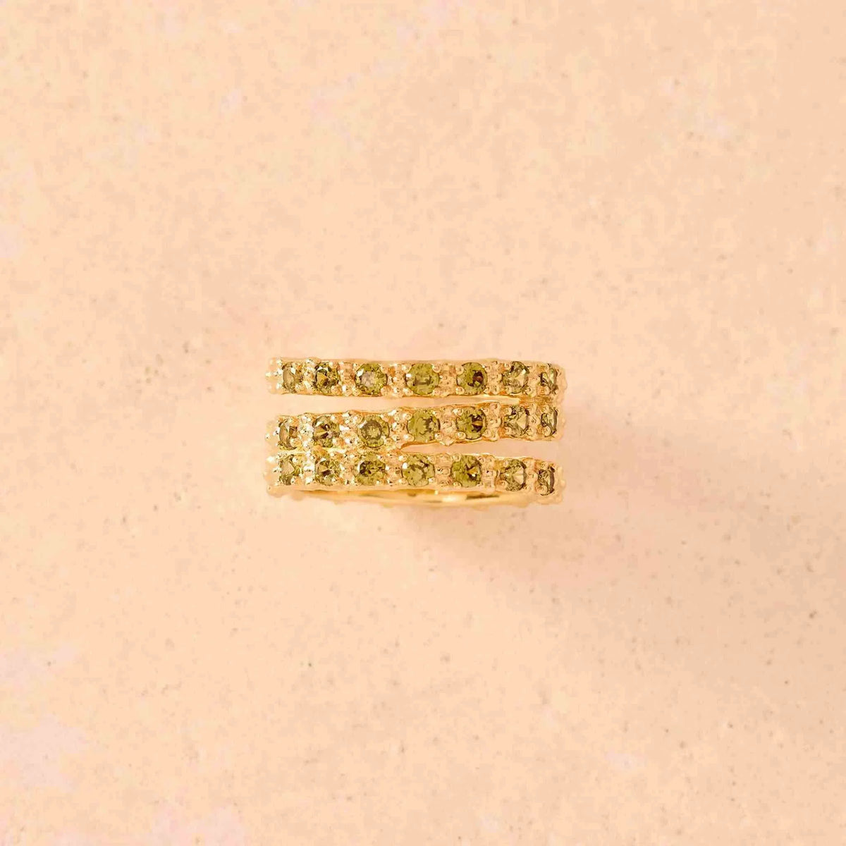 Agapée Jewelry Amalia Green Ring with three intertwined gold bands featuring vibrant green stones on the front