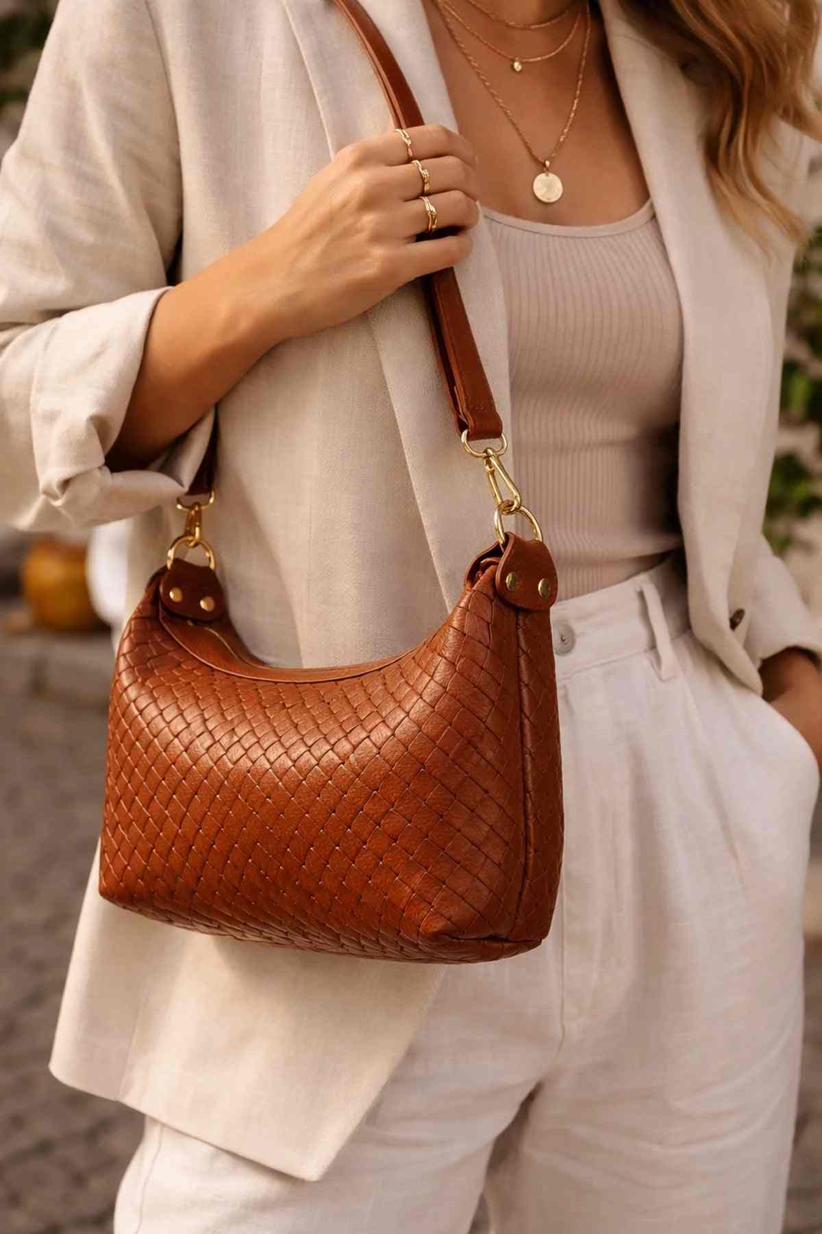 Cherry Paris brown leather handbag with woven texture and gold hardware worn with beige blazer and white pants