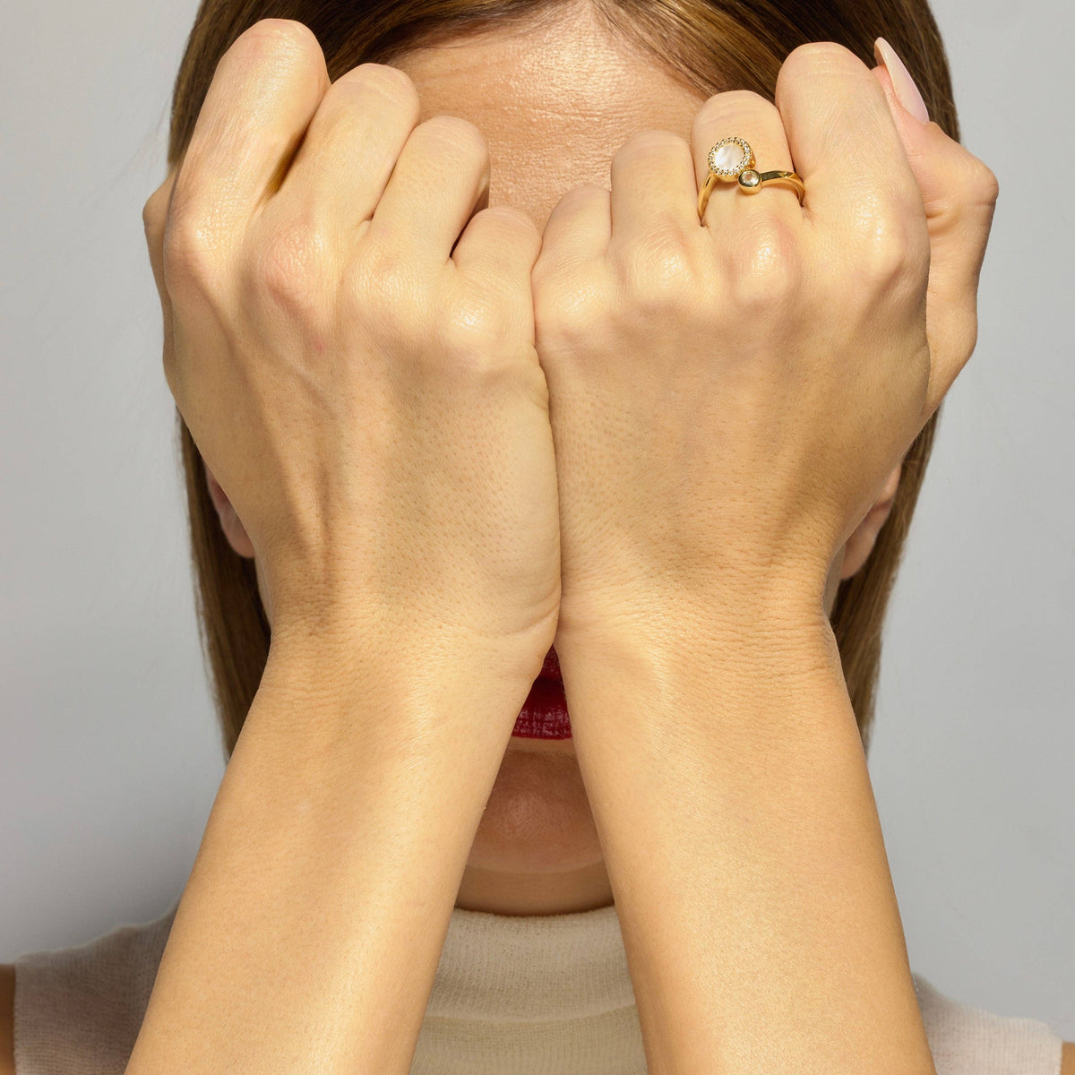 luxenter gold ring with a circular pearl and diamond design worn on a hand with light skin tone
