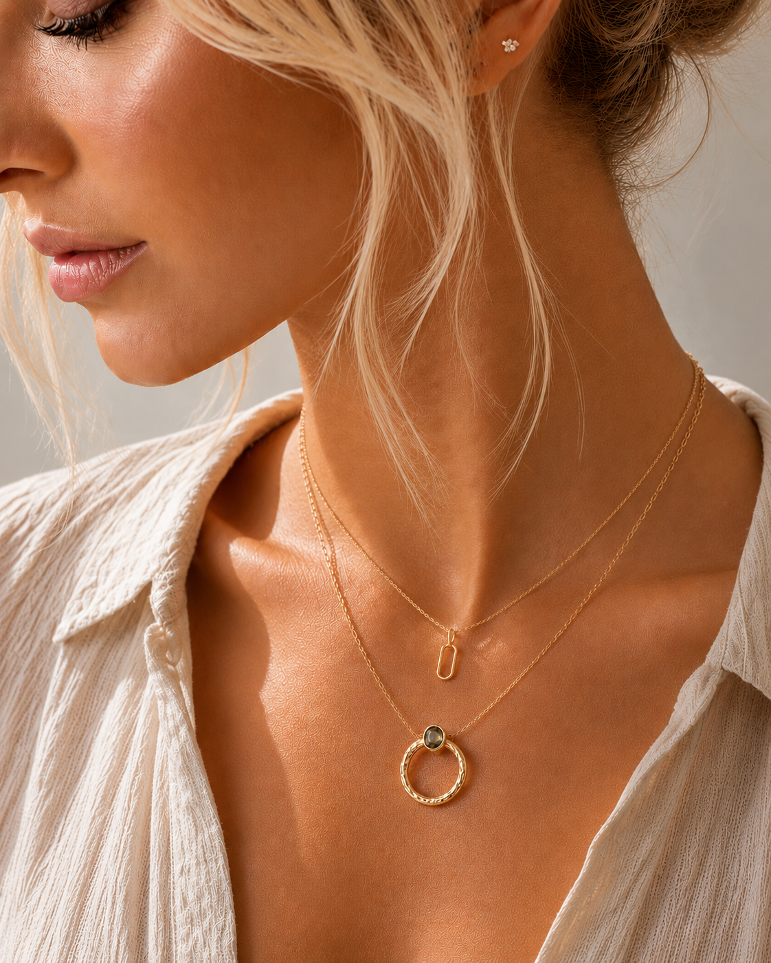 Necklace set with layered delicate gold chains featuring a small oval pendant and a textured circular pendant with a dark stone