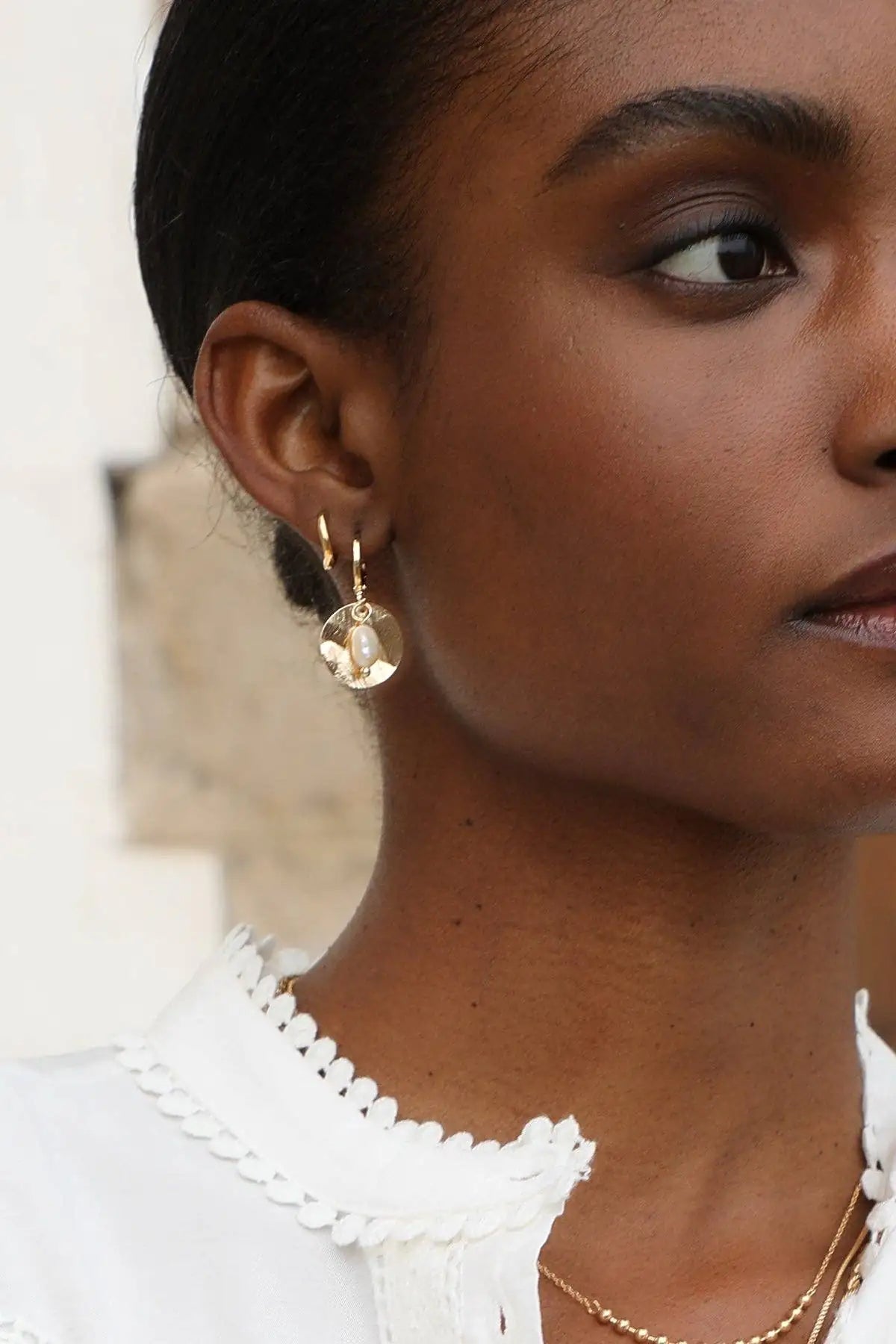  Refined gold-tone hoop earrings featuring an elegant charm detail for a sophisticated statement look