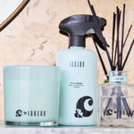 Janzen Room Spray, Musk Jasmine & Joy, 500ML bottle on a shelf with a candle and diffuser.