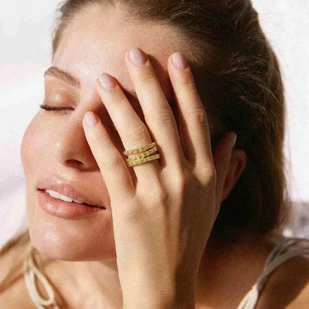 Agapée Jewelry Amalia Green Ring with three intertwined gold bands featuring small bead-like prongs and green stones on front side