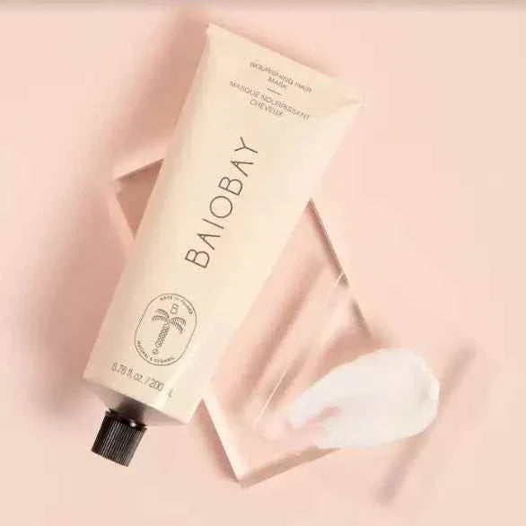 Baiobay Nourishing Hair Mask in beige squeeze tube with black cap and white cream on a clear platform, skincare treatment
