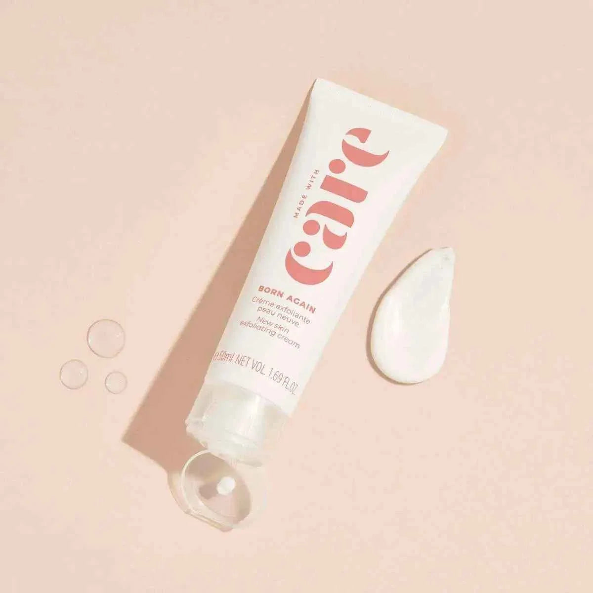 Care Exfoliating Cream in a white and pink squeeze tube with a creamy exfoliating texture swatch and water droplets on a beige surface