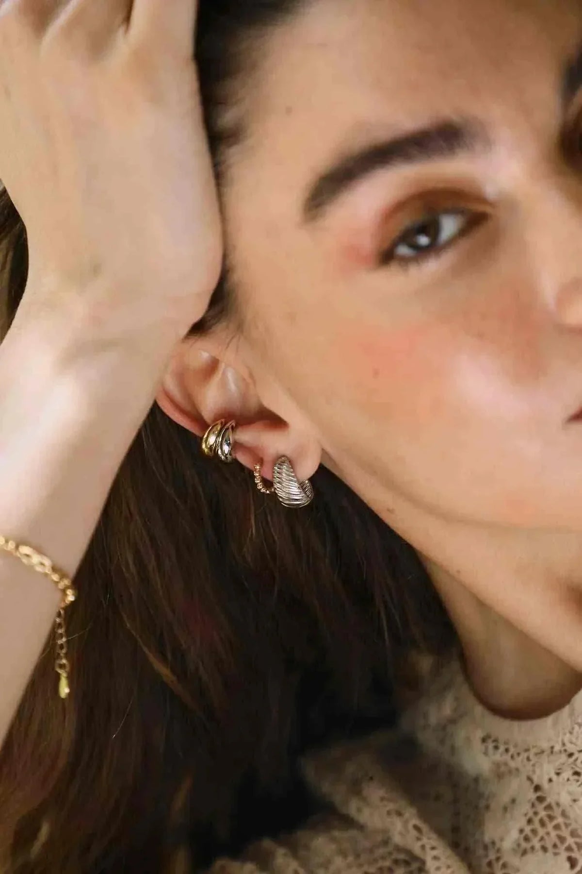 Fany oorbellen elegant textured gold-plated sterling silver hoop earrings worn on a woman's ear with a layered design