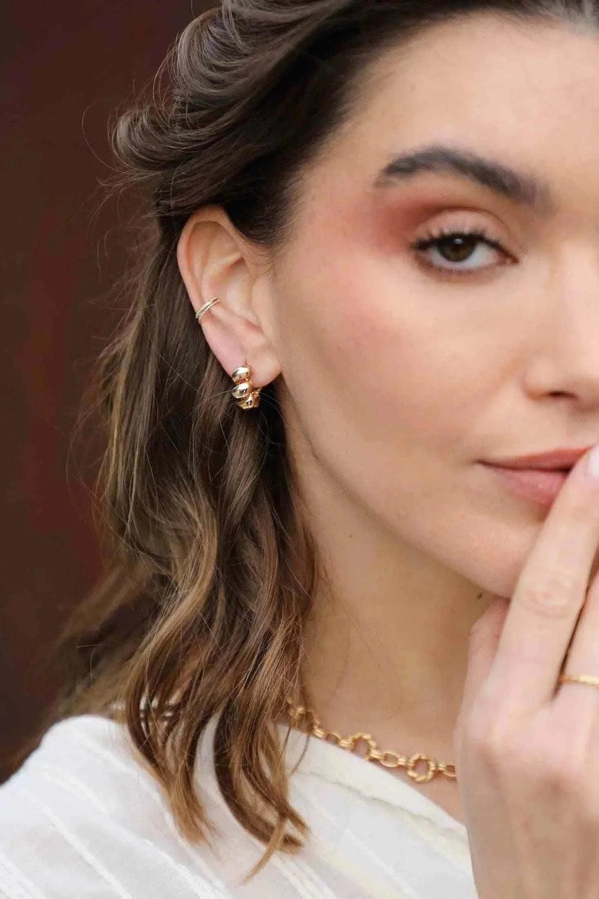Isel oorbellen gold-tone XL curl earrings with a bold, sculptural design on a woman with natural makeup and wavy hair