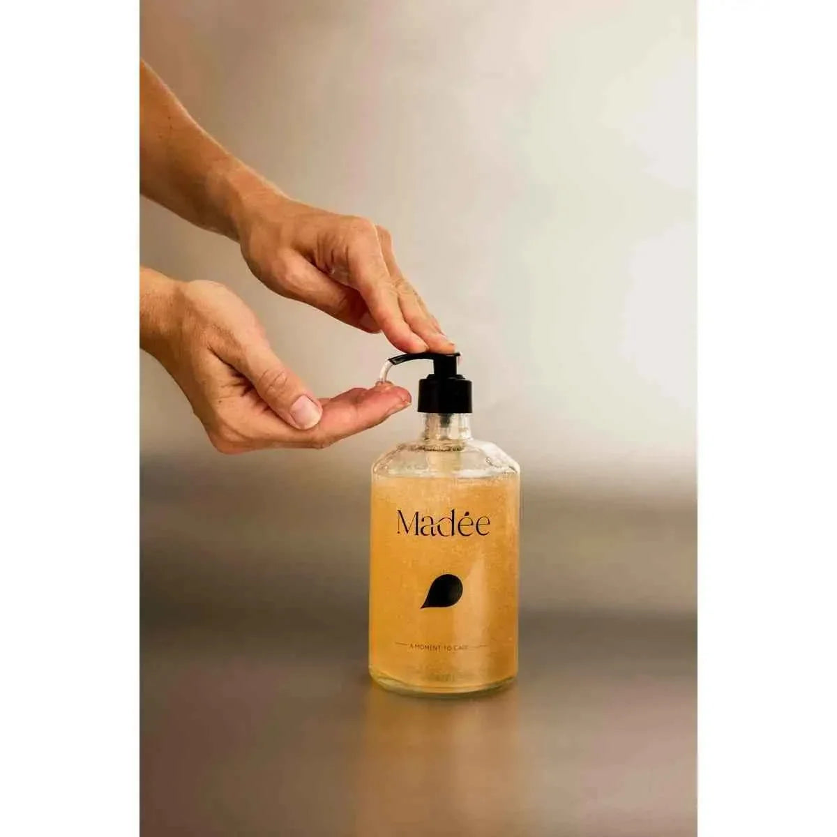 Madée Glass Hand Soap Set with clear glass bottle containing amber liquid soap and black pump dispenser