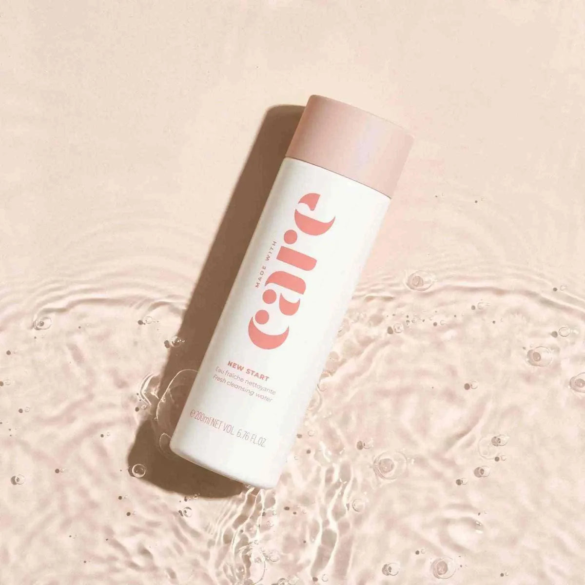Start - Cleansing Water in a white and soft pink bottle with minimalist typography floating on gentle rippling water surface